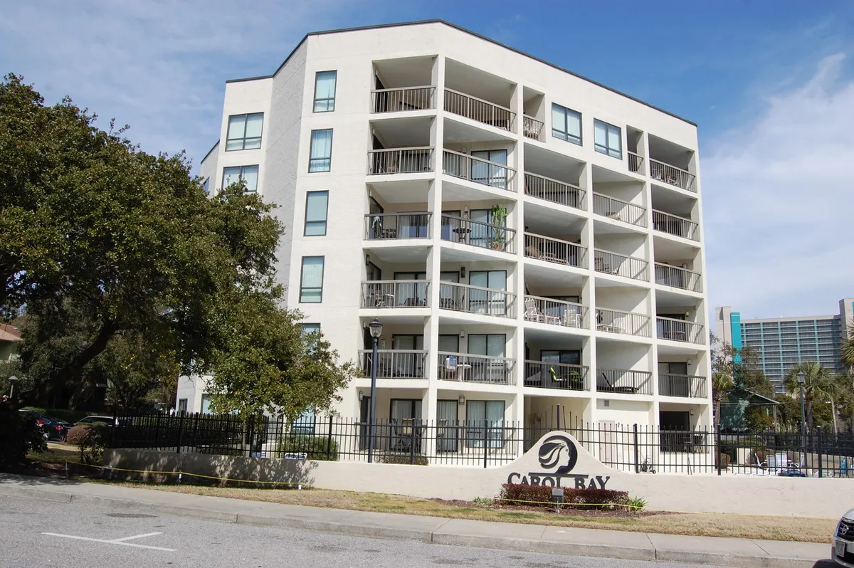 The exterior of a condominium building with balconies, a welcoming facade, and clear signage. Residents can enjoy relaxing on their private balconies or gather in the community’s outdoor spaces, which feel serene and inviting.